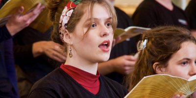 Ung kvinne synger fra et sanghefte