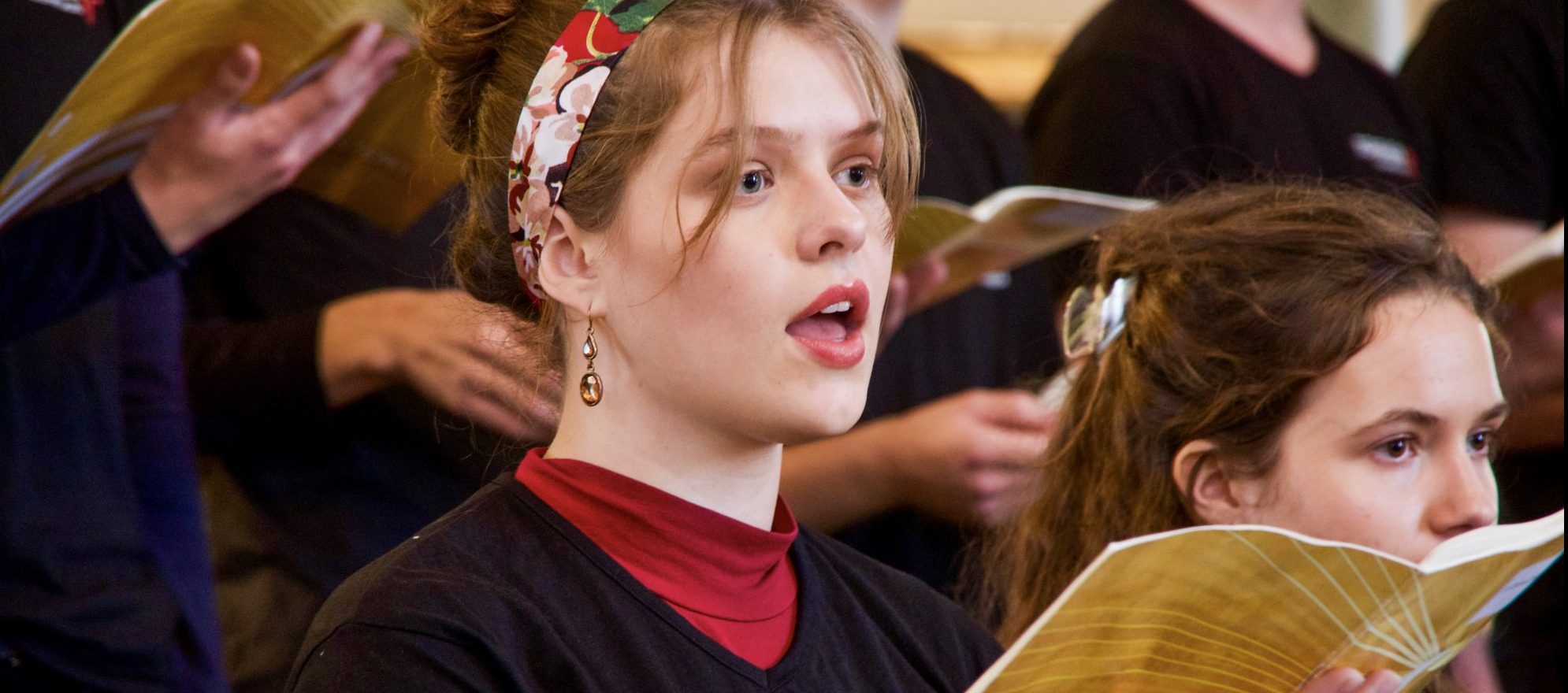 Ung kvinne synger fra et sanghefte